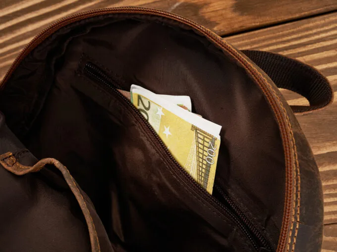 Zbliżenie wnętrza brązowego skórzanego plecaka z kieszenią i banknotem