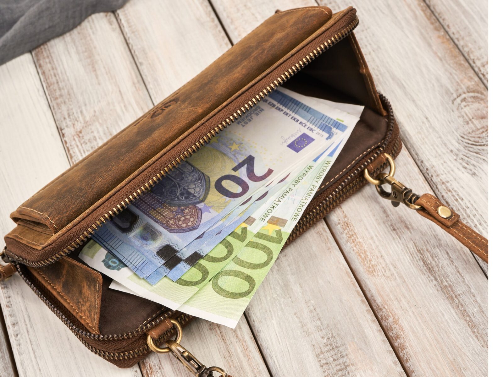Otwarta brązowa skórzana mini torebka z banknotami, widok z góry