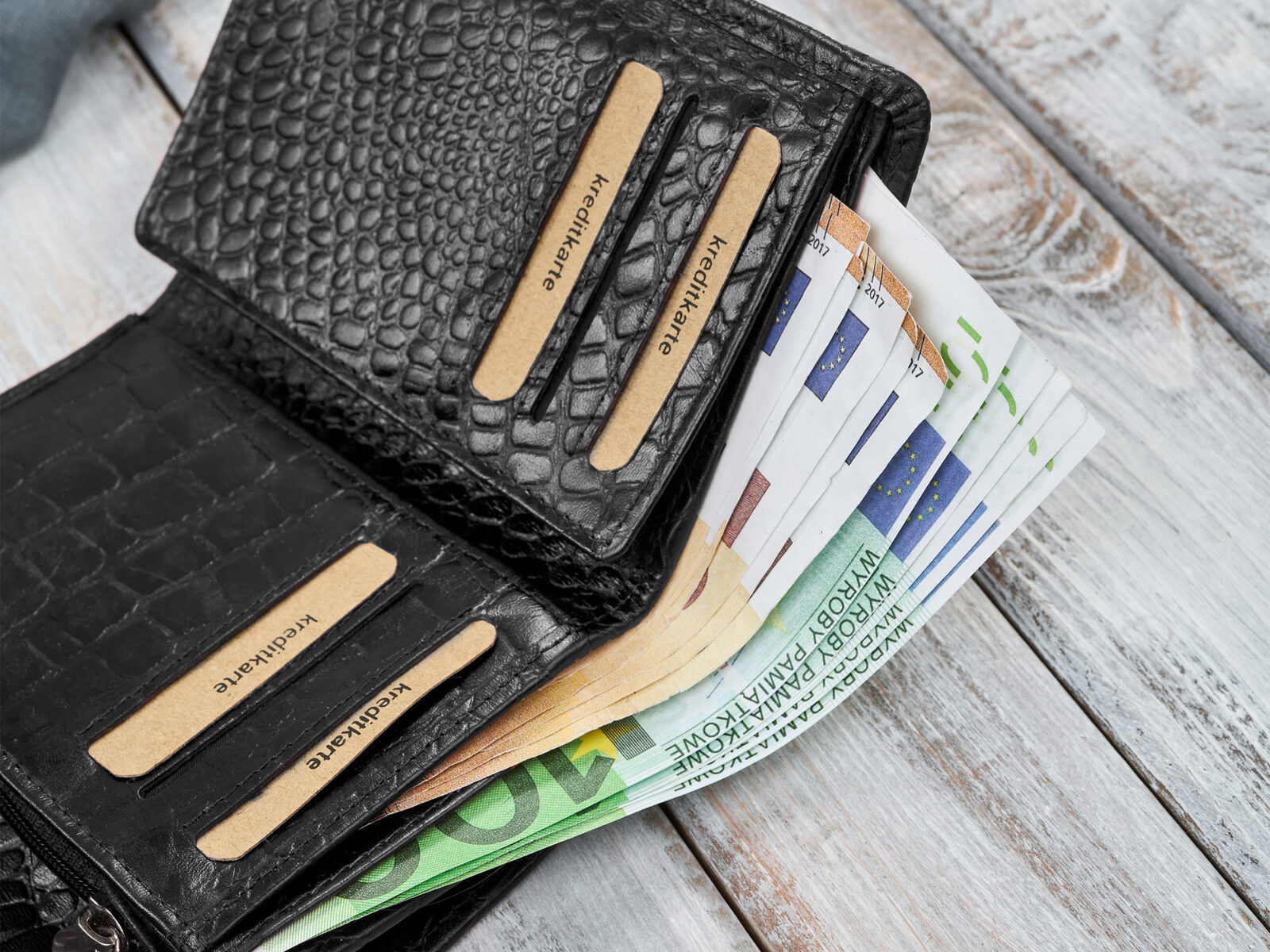 Otwarty czarny skórzany portfel damski z kieszeniami na karty i banknoty, faktura krokodyla