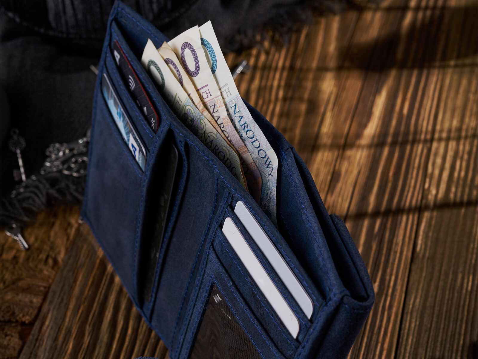 Otwarty granatowy portfel skórzany z kieszeniami i banknotami, zbliżenie detalu
